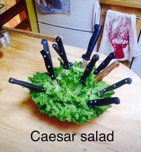 Caesar Salad: Salad with a bunch of knives in stabbed in it.