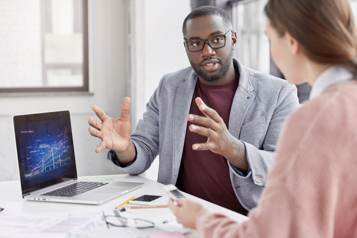 Man and women talking in front of a laptop.