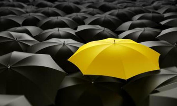 Yellow umbrella in a group of black umbrellas